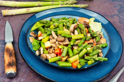 Tasty salad of green asparagus and fried mushrooms on a plate. Vegetable salad.