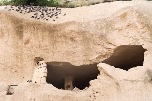 Dovecote carved into a cliff at the end of the Pigeon Valley, Güvercinlik Vadisi with a lot of Pigeons sitting on top, close to Uchisar, Cappadocia, Turkey 2022
