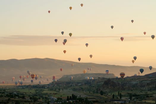 Many colorful hot air balloons over the landscape of the Red Valley, Rose Valley at sunrise, close to Goreme, Cavusin, Cappadocia, Turkey 2022