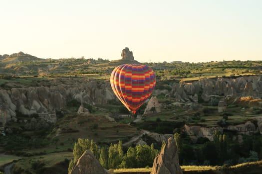 Colorful hot air balloon flying over the landscape of Cappadocia with its famous fairy chimneys, close to Göreme, Cappadocia, Turkey 2022
