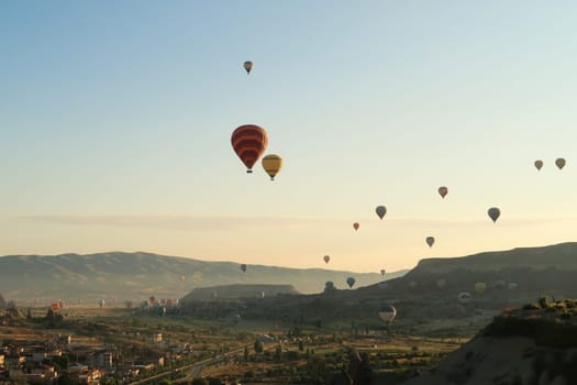Colorful hot air balloons flying over the landscape of the Red Valley, Rose Valley, close to Goreme, Cavusin, Cappadocia, Turkey 2022