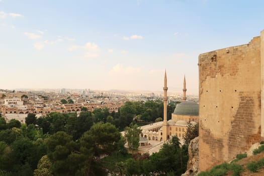 View from the hill of the Urfa Castle, Urfa Kalesi onto the Dergah Complex housing the Mevlidi Halil Camii Mosque and Abrahams Birth Cave and the city of Sanliurfa in the background, Sanliurfa, Turkey 2022