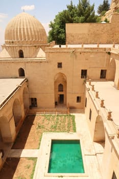 View into the inner courtyard of the Sultan Isa Medrese, Madrasa, Zinciriye Medrese with its green pool, pond, Mardin, Turkey 2022