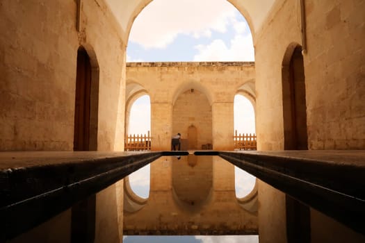 Water in a pond, pool reflecting the arches, vaults and doors of the Sultan Isa Medrese, Madrasa, Zinciriye Medrese in the old town of Mardin, Turkey 2022