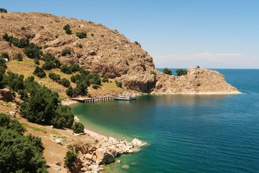 View onto the little pier, jetty on Akdamar Island on Lake Van, Van Gölü surrounded by a bay with intense blue, green, turquoise water, Van, Turkey 2022