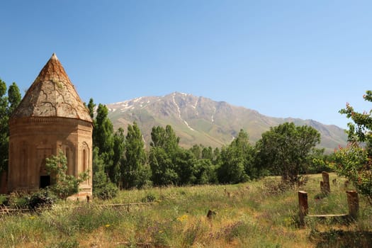 The Halime Hatun tomb, grave, mausoleum, Halime Hatun Kümbeti with the snow covered Mount Artos in the background and a few tombstones next to it, close to Lake Van, Van Gölü, Gevas, Turkey 2022