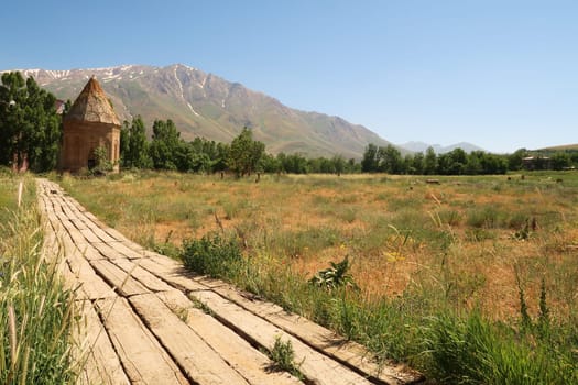 The Halime Hatun tomb, grave, mausoleum, Halime Hatun Kümbeti with the snow covered Mount Artos in the background and the boardwalk leading to it in the foreground, close to Lake Van, Van Gölü, Gevas, Turkey 2022