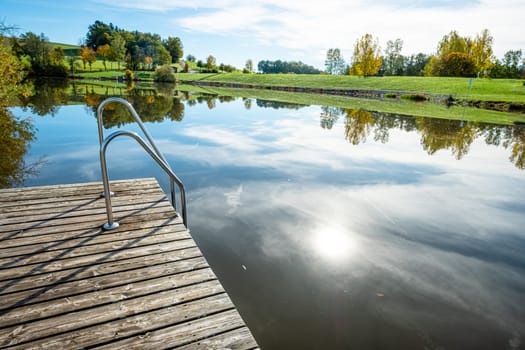 Dock at a lake with sun mirroring in water landscape