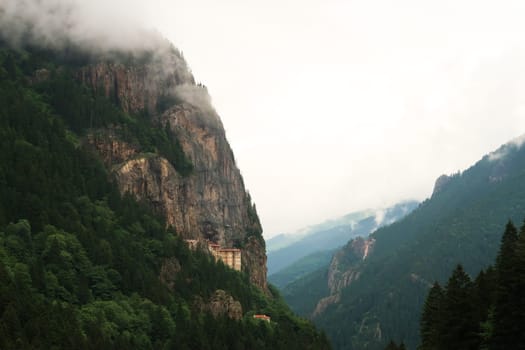 View onto the Sumela, Sümela Monastery, built on a cliff above a dense forest, fog coming up above the cliff, Trabzon, Turkey 2022
