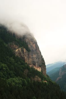 Picturesque view onto the Sumela, Sümela Monastery and the dense forest that surrounds it, fog coming up above the cliff that it is build on, Trabzon, Turkey 2022