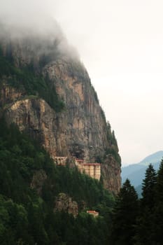 Spectacular view onto the Sumela, Sümela Monastery, built on a cliff above a dense forest, fog coming up above the cliff, Trabzon, Turkey 2022