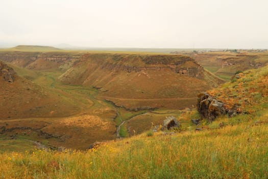 The Tsaghkotsadzor valley, gorge, canyon of the Alaca Cay river with man made caves next to the ancient site of Ani, an abandoned ruined armenian city, close to Kars, Turkey 2022