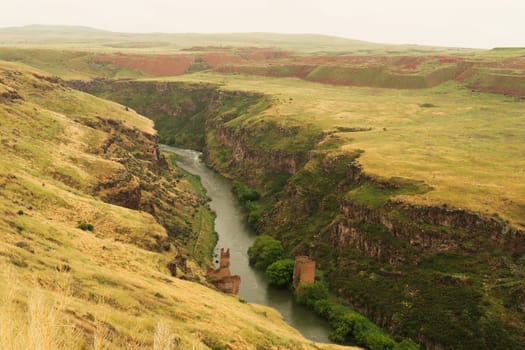 The destroyed, ruined bridge that was built over the Akhurian River down in the canyon, gorge that now forms the border between Turkey and Armenia at the ancient site of Ani, an abandoned ruined armenian city, close to Kars, Turkey 2022
