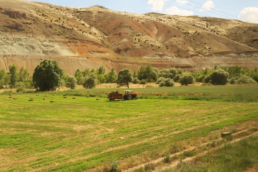 Passing farmers, farming, agriculture on the train ride in the Eastern Express, Dogu Ekspresi from Kars to Ankara, red tractor on a field, Turkey 2022