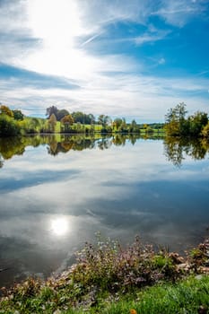 Lake meadow and blue sky with clouds in back lit of sun