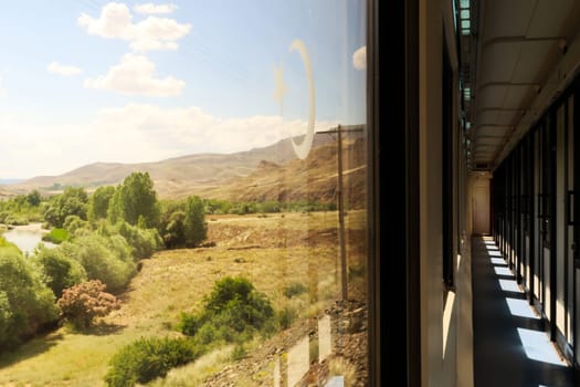 The beautiful landscape seen on the train ride in the Eastern Express, Dogu Ekspresi from Kars to Ankara, the interior of the train is visible, sun is shining in, Turkey 2022