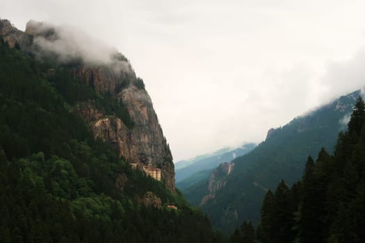 View onto the Sumela, Sümela Monastery and the dense forest that surrounds it, fog coming up above the cliff that it is build on, Trabzon, Turkey 2022