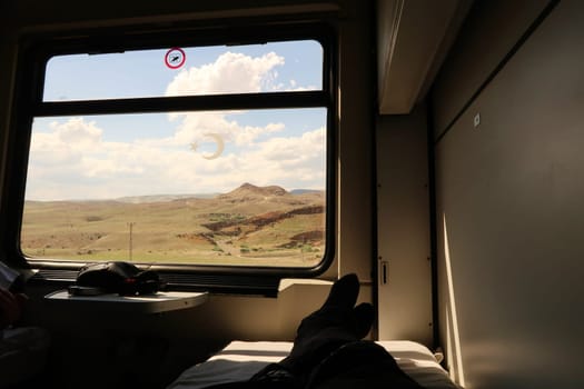 The view outside a window from the bed in the sleeping compartment, passenger cabin on the train ride in the Eastern Express, Dogu Ekspresi from Kars to Ankara, relaxing while watching the landscape, Turkey 2022
