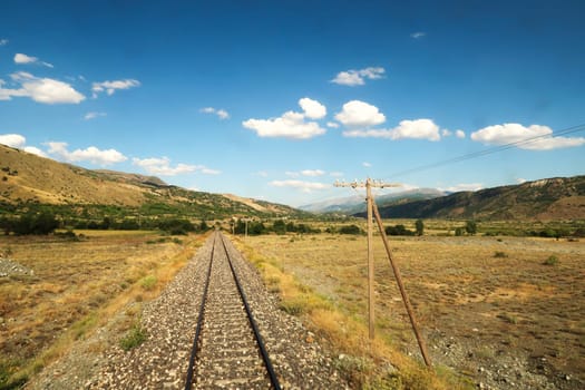 Back view on the train ride in the Eastern Express, Dogu Ekspresi from Kars to Ankara, endless train tracks are running through the spectacular landscape and disappearing at the horizon, Turkey 2022