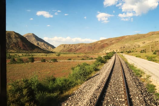 Back view on the train ride in the Eastern Express, Dogu Ekspresi from Kars to Ankara, train tracks are running through the spectacular landscape and disappearing in a tunnel, Turkey 2022