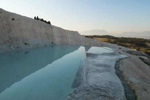 Intense blue water in the travertine terraces at Pamukkale in the early morning, Denizli, Turkey 2022