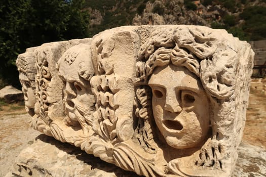 Stone with elaborate ancient relief of three theater masks in the ancient town of Myra, near Demre, Turkey 2022