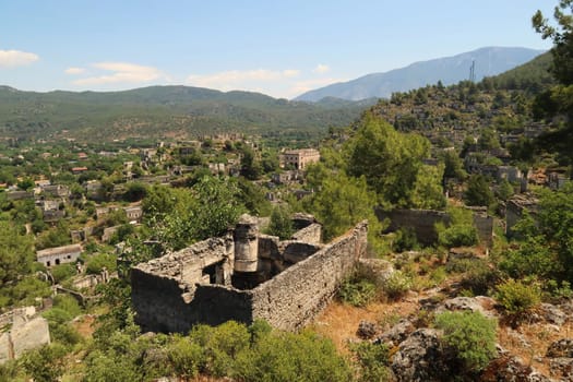 View on the abandoned village of Kayaköy, Livissi with a traditional house with chimney and without roof in the foreground, close to Fethiye, Turkey 2022