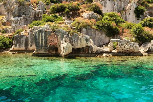 Submerged structures in the foreground, ruins of buildings, remaining wall with door in the background at the ancient sunken city of Kekova, Kekova Island, Demre, Turkey 2022