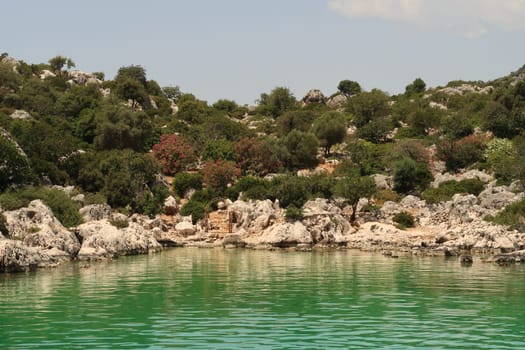 The Burc Koyu Bay, green water in the foreground and metall doorway and lush vegetation in the background, close to Demre, Turkey 2022