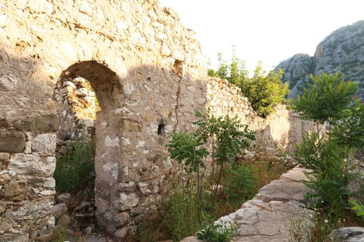 A wall with a door inside the ruins of Church A at the ancient site of Olympos, Olympus, plants, bushes and trees are overgrowing the area, close to Antalya, Turkey 2022