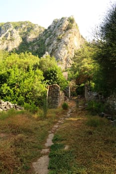 Trail leading through the ruins across the river at the ancient site of Olympos, Olympus with a mountain in the background, close to Antalya, Turkey 2022