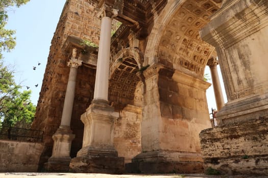 Pigeons landing on the wall next to the Hadrians Gate, famous ancient roman landmark in Antalya, Turkey 2022