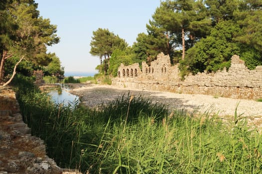 The Göksu river flowing into the Cirali Koyu Bay with the ruins of a bath house next to it at the ancient site of Olympos, Olympus, Turkey