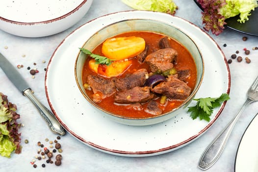 Stewed deer goulash in sauce, venison goulash. Deer ragout on rustic wooden surface.