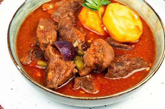 Stewed deer goulash in sauce, venison goulash. Deer ragout on rustic wooden surface.