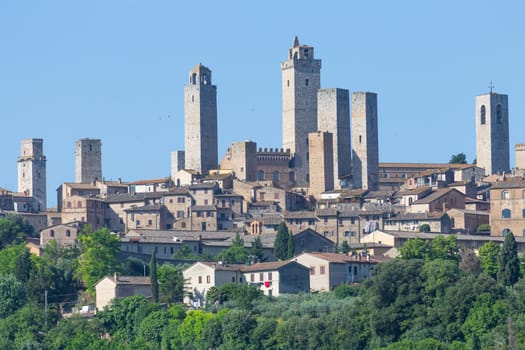 San Gimignano village, Italy - green countryside, blue sky, hill panorama with town and towers