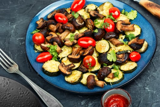 Roasted vegetables. Mushrooms, zucchini and tomatoes baked in the oven on plate. Space for text.