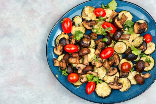Roasted vegetables. Mushrooms, zucchini and tomatoes baked in the oven on plate. Space for text.