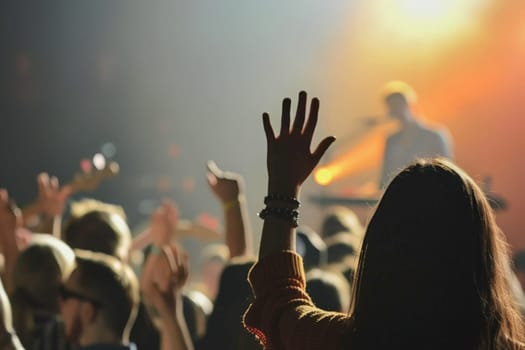 A vibrant crowd of people energetically dancing with their hands raised under colorful lights at a concert.