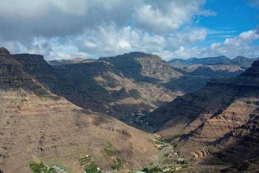 Mountains with a small village in the valley on the Canary Island of Gran Canaria in Spain, with blue sky and clouds