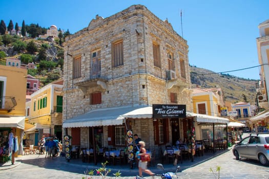 SYMI, Greece - 03 JUNE 2021. A grill house restaurant Symi town near harbour where tourists linger. Most beautiful and romantic district in the whole Aegean.