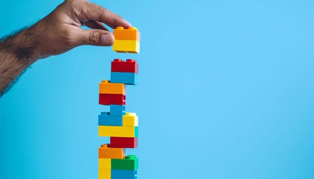 Man hand building with colorful Lego. Hand build blocks and going to add the final piece between the gap to complete, concept of help solution, solve the disconnect problem. Hobby toys Copy space
