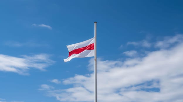 A flag with a red and white pattern flutters proudly against a bright blue sky.