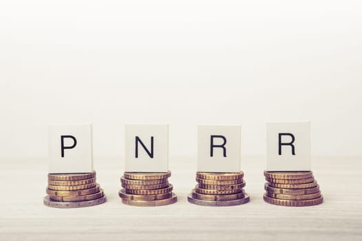 Stacks of coins with PNRR letters on white background. UE economy concept.