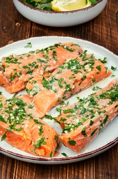 Fresh raw salmon fillet fish in garlic herbs marinade ready for baking. Close up.