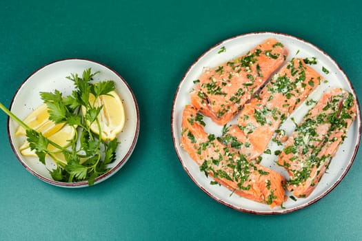 Fresh raw salmon fillet fish in garlic herbs marinade ready for baking. Close up.