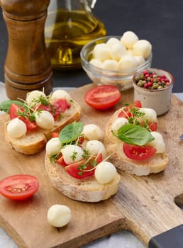 Round mozzarella, cherry tomatoes and microgreens on a piece of white bread, a healthy sandwich