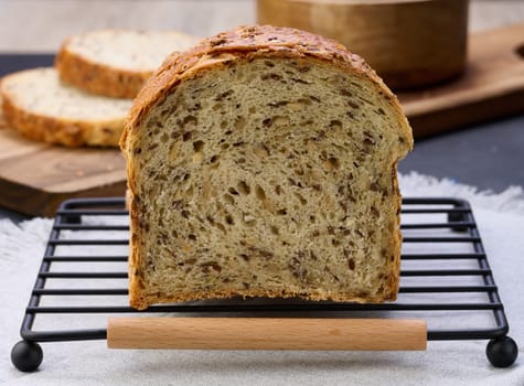 Sliced ​​white wheat flour bread with flax seeds on a wooden board, close up