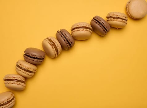Chocolate macarons on a yellow background, dessert. Top view