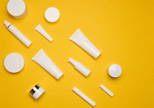 Various types of white plastic packaging, bottle, jar, tube on a yellow background. Container for cosmetics, top view